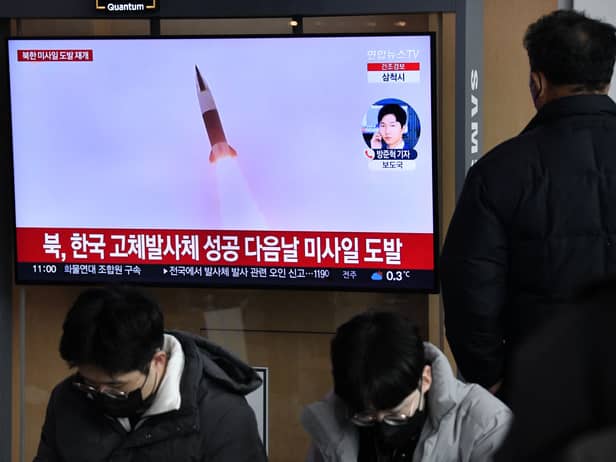 A man watches a television screen showing a news broadcast with file footage of a North Korean missile test, at a railway station in Seoul on December 31, 2022