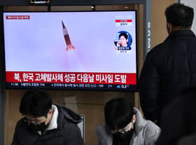 A man watches a television screen showing a news broadcast with file footage of a North Korean missile test, at a railway station in Seoul on December 31, 2022