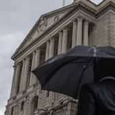 A commuter walks through heavy rain near the Bank of England, London.