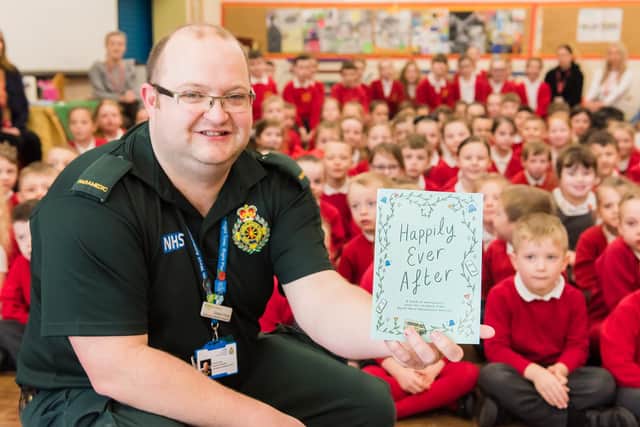A North West Ambulance Service paramedic shows the 'Happily Ever After' book to children