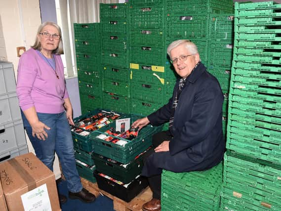 Operations Manager Ros Duerden shows Rt Rev. Julian Henderson, Bishop of Blackburn, how low the supply of tinned tomatoes is at their Foodbank
