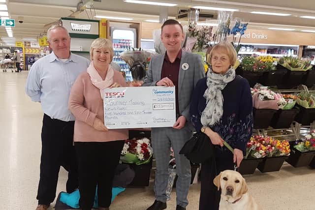Marjorie and Alan Dunderdale receive a cheque from Tesco along with Ann Kay and her guide dog Dixie.