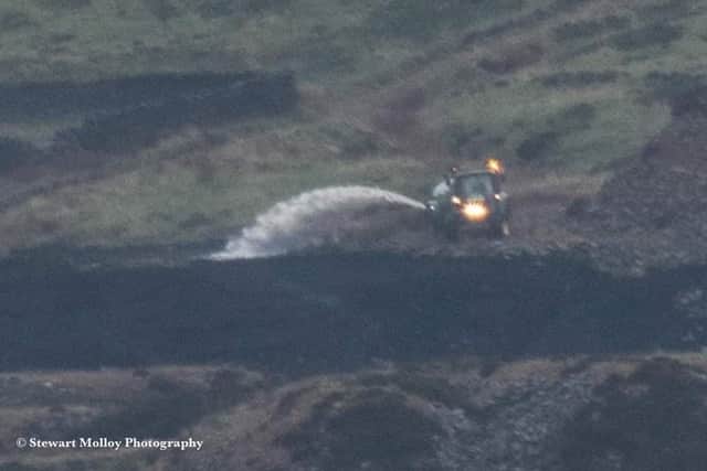 A farmer damping down the scorched moorland with a tractor equipped with a water tank. Credit: Stewart Molloy