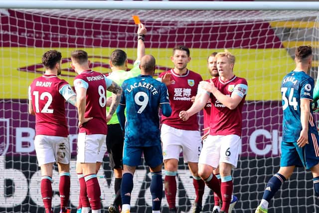 Referee Andre Marriner (C) initially shows a red card for handball to send off Burnley's Dutch defender Erik Pieters (4R) as other players react, a decision that was reversed after VAR review found no offense.