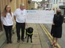 (From left) Receiving Community Champions funding for Braille IT are Alison Hargeaves, Chris Tattersall and Goughy the dog with Persimmon Homes sales director Diane Finch outside the library in Clitheroe.