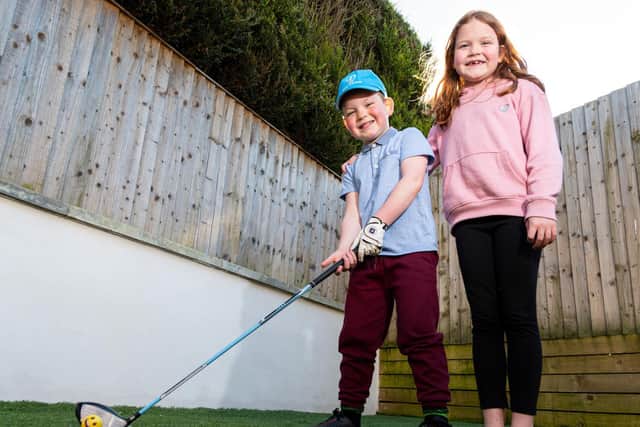 Ritchie gets in some golf practise watched by big sister Millie (eight)