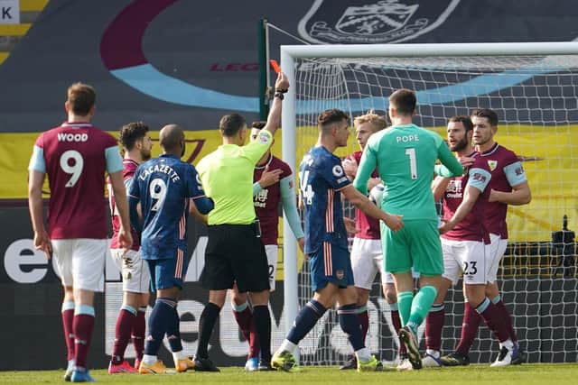Referee Andre Marriner awards Erik Pieters of Burnley a red card, following a potential hand ball inside the penalty area, which is later overruled following a VAR review during the Premier League match between Burnley and Arsenal at Turf Moor on March 06, 2021.