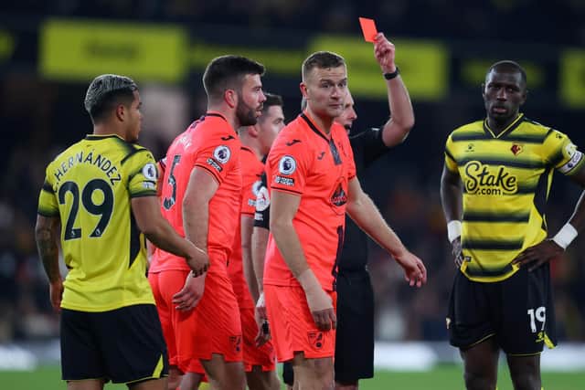 Referee, Mike Dean shows Emmanuel Dennis of Watford (not pictured) a red card during the Premier League match between Watford and Norwich City at Vicarage Road on January 21, 2022 in Watford, England.