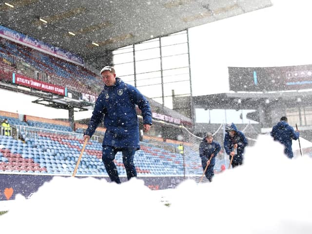 A general view inside the stadium as groundsman attempt to clear snow from the pitch prior to the Premier League match between Burnley and Tottenham Hotspur at Turf Moor on November 28, 2021 in Burnley, England.