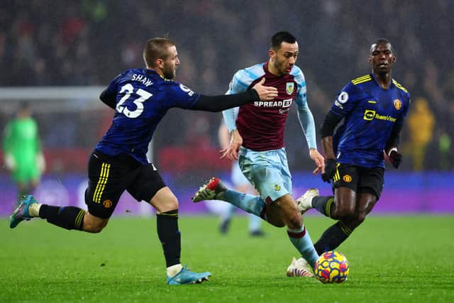 Dwight McNeil of Burnley is challenged by Luke Shaw (L) and Paul Pogba of Manchester United (R) during the Premier League match between Burnley and Manchester United at Turf Moor on February 08, 2022 in Burnley, England.