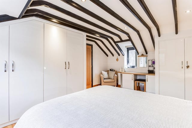 White wardrobes are a stark contrast to the ceiling beams in this lovely bedroom.