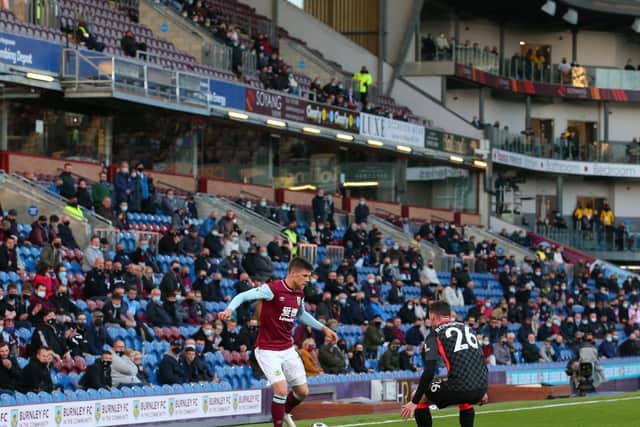 Johann Gudmundsson of Burnley is closed down by Andrew Robertson of Liverpool as fans watch on behind during the Premier League match between Burnley and Liverpool at Turf Moor on May 19, 2021 in Burnley, England.