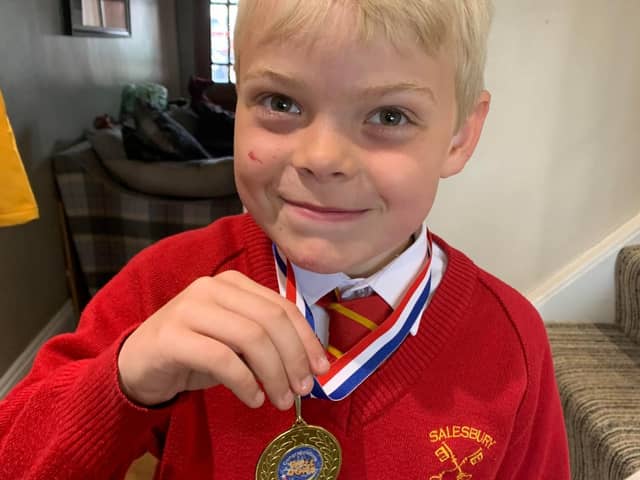Alfie Holden proudly shows off his medal after completing the 100 laps challenge