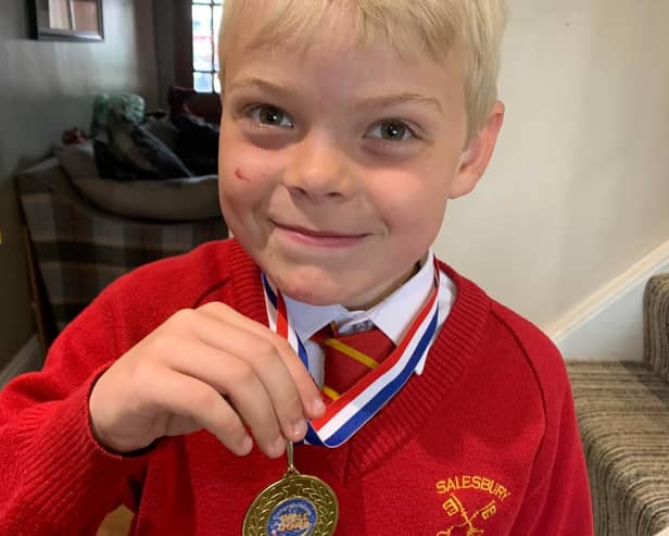 Alfie Holden proudly shows off his medal after completing the 100 laps challenge