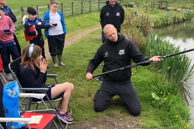 Mark demonstrates how to use a fishing rod to a group at one his wellbeing angling sessions