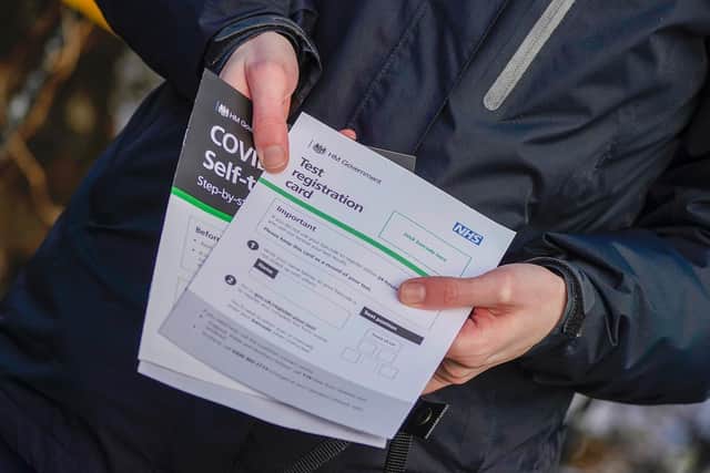 A person poses with their Test registration card after being tested at Our Lady's RC Church in Moss Side.