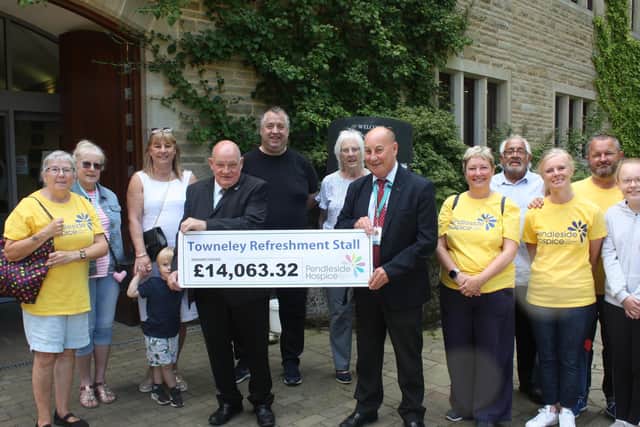 Mr Jackson receiving a cheque from Mr Darwen, watched by hospice volunteers and supporters, at Towneley Hall.