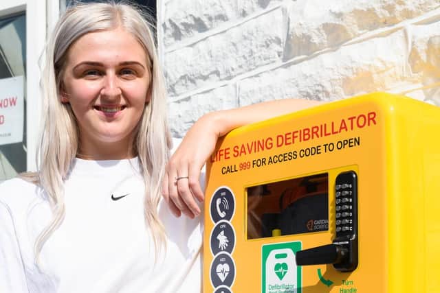 Jodie pictured with the newly installed defibrillator she raised funds for
