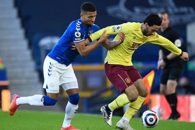 Dwight McNeil of Burnley is challenged by Mason Holgate of Everton during the Premier League match between Everton and Burnley at Goodison Park on March 13, 2021 in Liverpool, England.