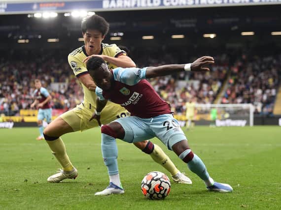 Maxwel Cornet of Burnley holds off Takehiro Tomiyasu of Arsenal during the Premier League match between Burnley and Arsenal at Turf Moor on September 18, 2021 in Burnley, England.