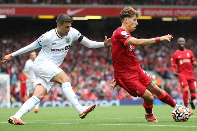 Kostas Tsimikas of Liverpool turns with the ball away from Matthew Lowton of Burnley during the Premier League match between Liverpool and Burnley at Anfield on August 21, 2021 in Liverpool, England.