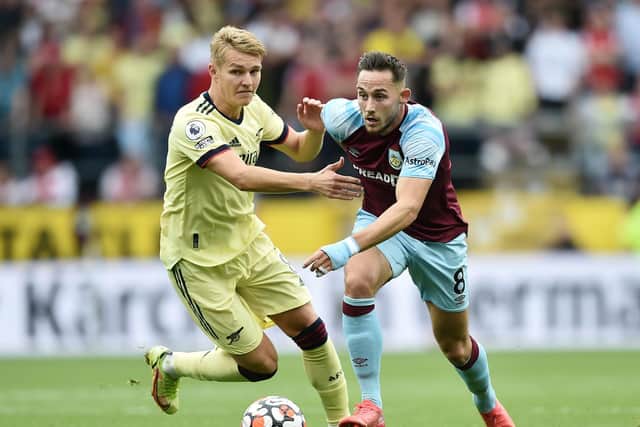 Josh Brownhill of Burnley is challenged by Martin Odegaard of Arsenal during the Premier League match between Burnley and Arsenal at Turf Moor on September 18, 2021 in Burnley, England.