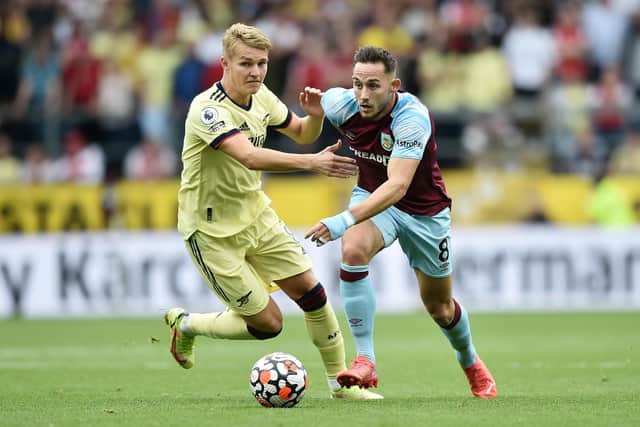 Josh Brownhill of Burnley is challenged by Martin Odegaard of Arsenal during the Premier League match between Burnley and Arsenal at Turf Moor on September 18, 2021 in Burnley, England.