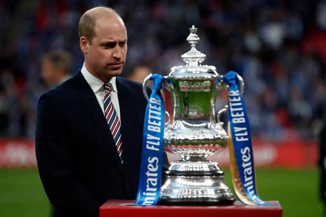 Britain's Prince William, Duke of Cambridge stands by the winner's trophy as the Leicester players celebrate victory after the English FA Cup final football match between Chelsea and Leicester City at Wembley Stadium in north west London on May 15, 2021.