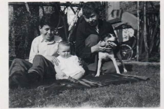 Peter (holding the dog) with his brother Geoff and their baby sister Janet