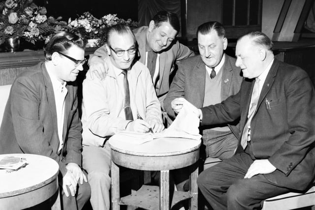 Association secretary D. Cartledge and president J. Gibbons watch while Vic Bell records the names, and his fellow competition organiser, Arthur Coates, conducts the draw with J. Winder, a member of the committee, at the Clarion Club, Smirthwaite Street, Burnley.