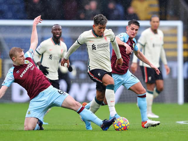 BURNLEY, ENGLAND - FEBRUARY 13: Roberto Firmino of Liverpool is challenged by Ben Mee and Ashley Westwood of Burnley during the Premier League match between Burnley and Liverpool at Turf Moor on February 13, 2022 in Burnley, England. (Photo by Alex Livesey/Getty Images)
