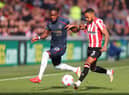 BRENTFORD, ENGLAND - MARCH 12: Maxwel Cornet of Burnley battles for possession with Rico Henry of Brentford during the Premier League match between Brentford and Burnley at Brentford Community Stadium on March 12, 2022 in Brentford, England.