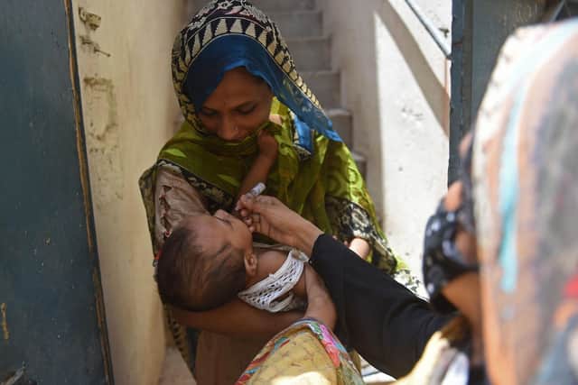 A health worker administers polio vaccine drops to a child during a door-to-door polio vaccination campaign