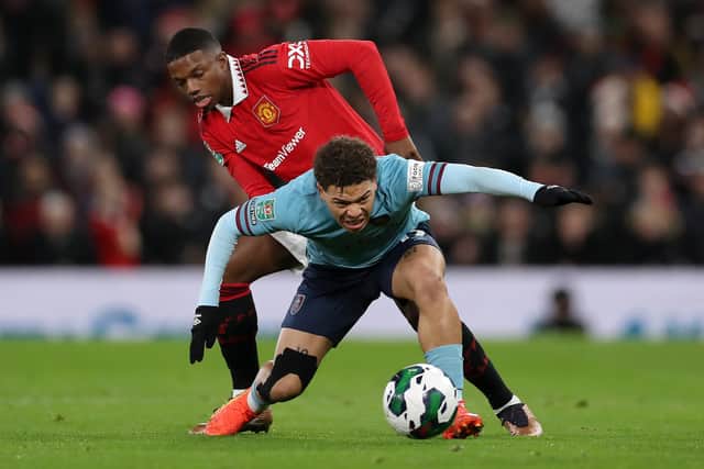 MANCHESTER, ENGLAND - DECEMBER 21: Manuel Benson of Burnley is challenged by Tyrell Malacia of Manchester United during the Carabao Cup Fourth Round match between Manchester United and Burnley at Old Trafford on December 21, 2022 in Manchester, England. (Photo by Lewis Storey/Getty Images)