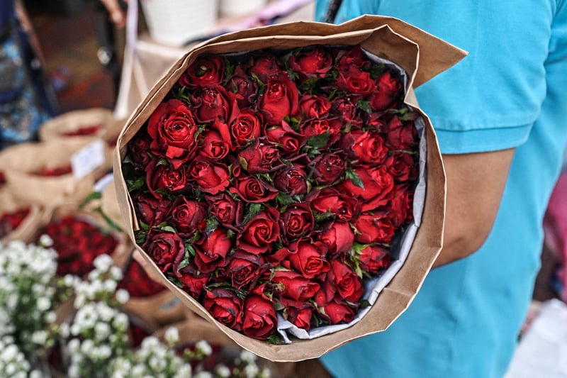 A flower vendor handles a bouquet of roses on the eve of Valentine's Day. (Photo by LILLIAN SUWANRUMPHA/AFP via Getty Images)