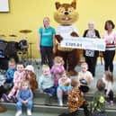 Penny Squirrel and Leah Hooper receive the cheque from Janet Kershaw and Julie Williams with some of the children at the weekly meeting in Cliviger