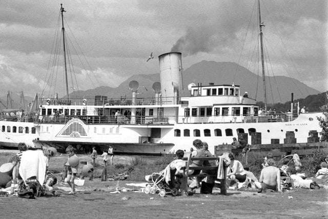 Holidaymakers enjoy the sun in Balloch as the Maid of the Forth paddle steamer passes by in Loch Lomond, July 1972