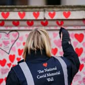 A volunteer from the Covid-19 Bereaved Families for Justice campaign group paints a heart on the National Covid Memorial Wall opposite the Palace of Westminster in central London, which remembers people who have died of the virus. Picture date: Friday January 28, 2022.