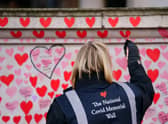 A volunteer from the Covid-19 Bereaved Families for Justice campaign group paints a heart on the National Covid Memorial Wall opposite the Palace of Westminster in central London, which remembers people who have died of the virus. Picture date: Friday January 28, 2022.