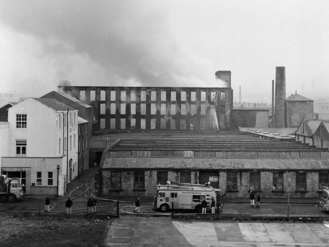 Britannia Mill, Lune Street, Padiham. March 11, 1971.

The morning after - a rooftop picture of the gutted mill, taken by Express chief photographer, Jerry Bradley, showing firemen using hoses to keep the blaze under control.

Firemen continued damping down work last night at the Padiham mill which was gutted by fire in the early hours of yesterday morning, 11th March 1971. A spokesman for Lancashire County fire Brigade said yesterday afternoon: "It is difficult to say how long we will be needed, but there is no doubt that damping down will take another 12 hours." In charge of the 150 firemen who tackled the fire was the county's chief Fire Officer, Mr P. Darby.

Most of the 70 workers employed at the firm, Padiham Cotton and Cotton Waste Co. Ltd, Britannia Mill, were sent home yesterday morning, and the rest helped with salvaging operations as firemen stayed at the scene in case the fire flared up again. A police constable on duty spotted the blaze about 1.20 a.m., and 25 fire appliances were brought from all over Lancashire, including Manchester and the Fylde Coast. The Divisional Fire Officer, Mr F. J. Kelly said: "We found it a hazardous and dangerous job and, initially, there was so much smoke that the only means of entry was by wearing breathing apparatus". The premises of Padiham Paints is next door to the gutted mill, and one of the major problems for firemen was in keeping the blaze away from the building.