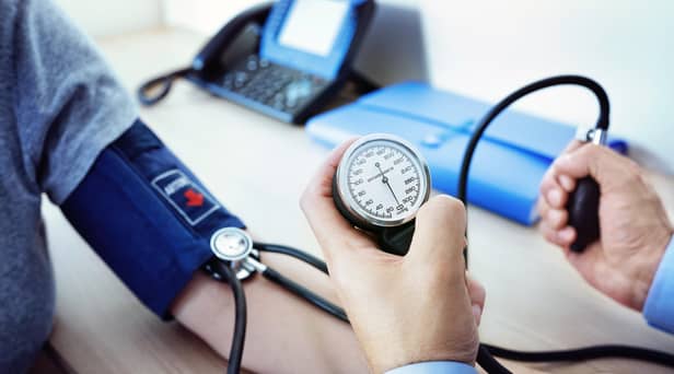 A GP examines a male patient and checks his blood pressure