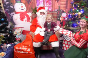Father Christmas and one of his elves bring a smile to one young visitor