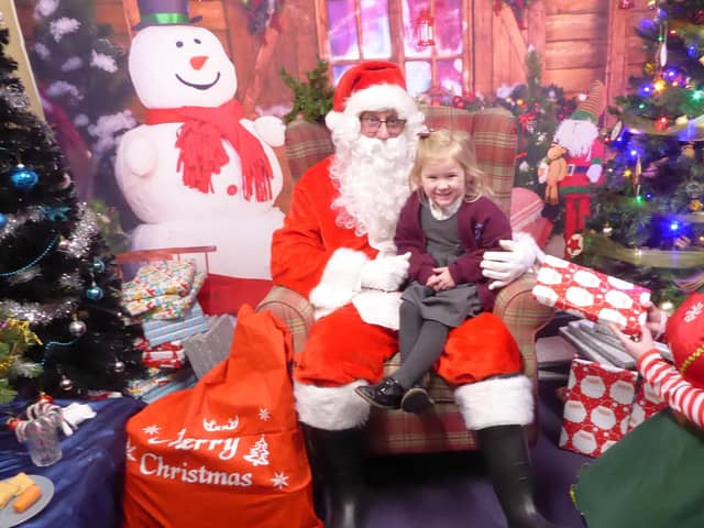 Father Christmas and one of his elves bring a smile to one young visitor