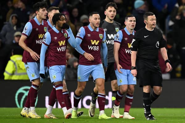 English Referee Tony Harrington (R) is followed by Burnley players as the VAR (Video Assistant Referee) is asked to look at the late Luton goal during the English Premier League football match between Burnley and Luton Town at Turf Moor in Burnley, north-west England on January 12, 2024. (Photo by Oli SCARFF / AFP) / RESTRICTED TO EDITORIAL USE. No use with unauthorized audio, video, data, fixture lists, club/league logos or 'live' services. Online in-match use limited to 120 images. An additional 40 images may be used in extra time. No video emulation. Social media in-match use limited to 120 images. An additional 40 images may be used in extra time. No use in betting publications, games or single club/league/player publications. /  (Photo by OLI SCARFF/AFP via Getty Images)
