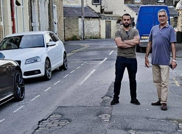 County Coun. Usman Arif and Burnley shopkeeper Mubashar Lone in front of potholes on a Burnley street