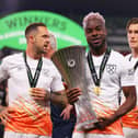 Maxwel Cornet celebrates with the trophy, as Danny Ings watches on