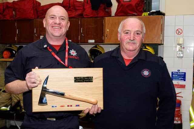 Firefighter Peter McMullen (right) is presented with an axe in recognition of his 40 years of service by Crew Manager Keith Whitley. Photo: Kelvin Stuttard