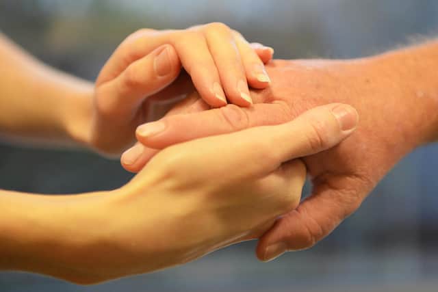 A support worker holding the hand of a vulnerable person.