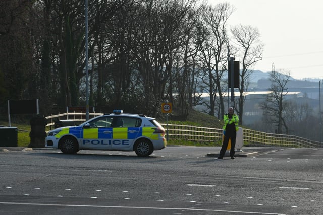 A police officer prevents entry to the road leading to the fire