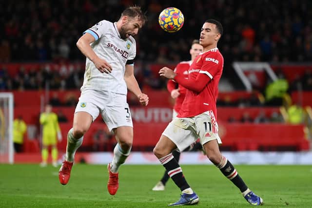 MANCHESTER, ENGLAND - DECEMBER 30: Charlie Taylor of Burnley competes for a header with Mason Greenwood of Manchester United during the Premier League match between Manchester United and Burnley at Old Trafford on December 30, 2021 in Manchester, England.